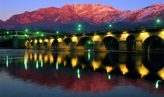 Ponte Azzone Visconti illuminato di sera con Monte Resegone sullo sfondo