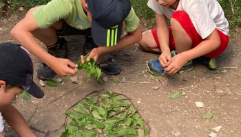 Bambini che giocano con rami e foglie durante una caccia al tesoro archeologica